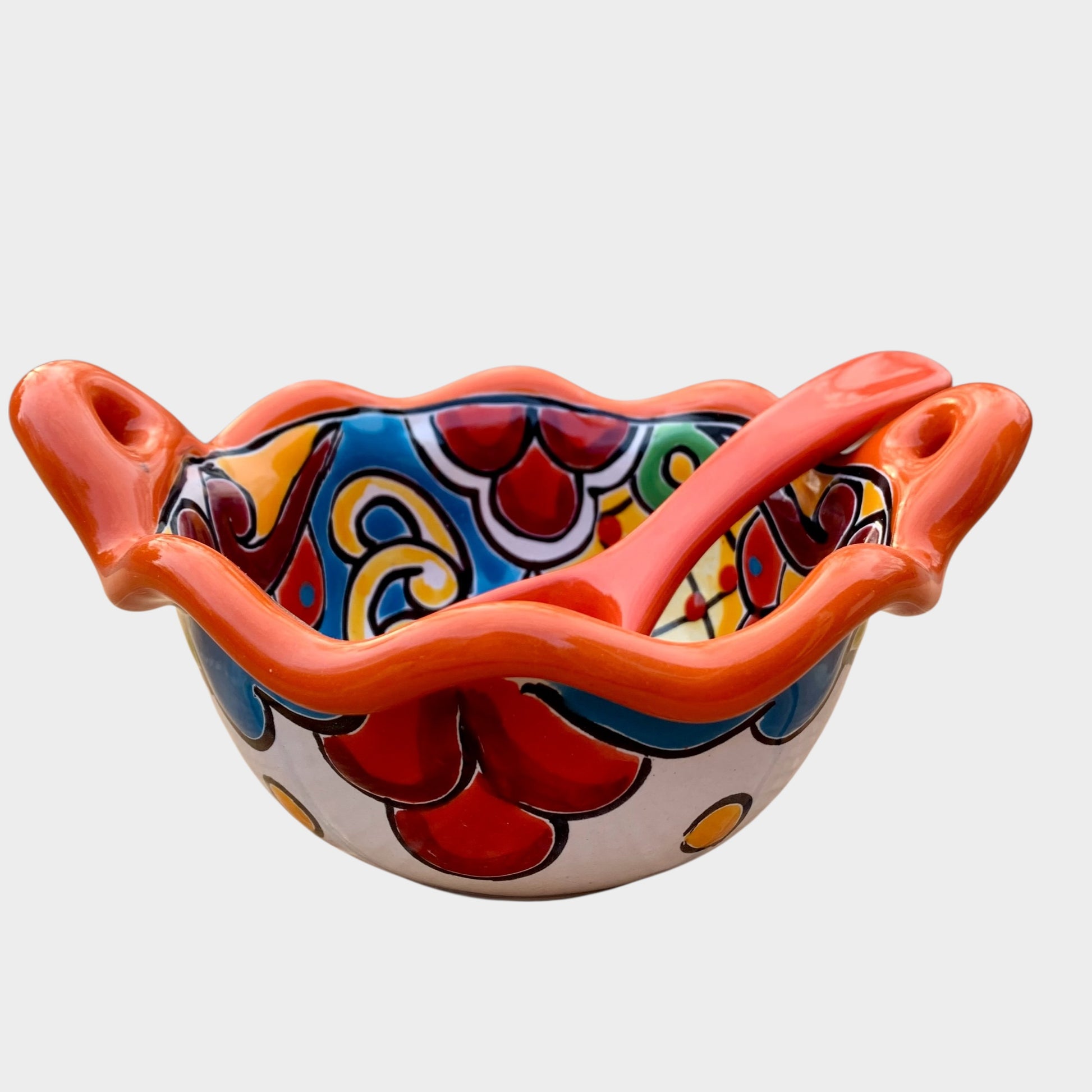 Colorful talavera salsa bowl with floral patterns and spoon on a white background Side view