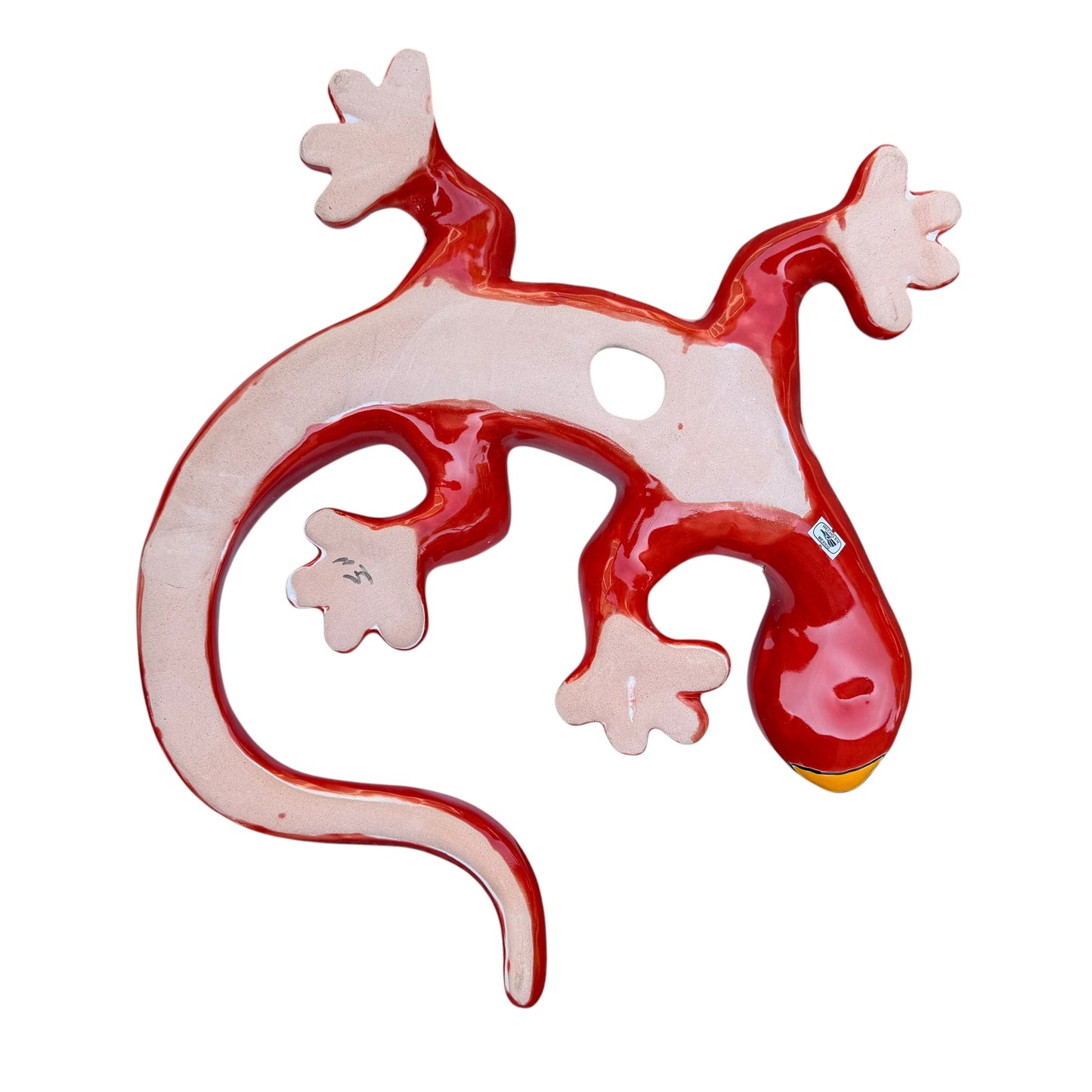 A colorful Talavera ceramic wall salamander lizard art piece with a glossy finish, featuring a red head and tail with a patterned body, displayed against a white brick wall background, right side body view, back view with hanging hole. 
