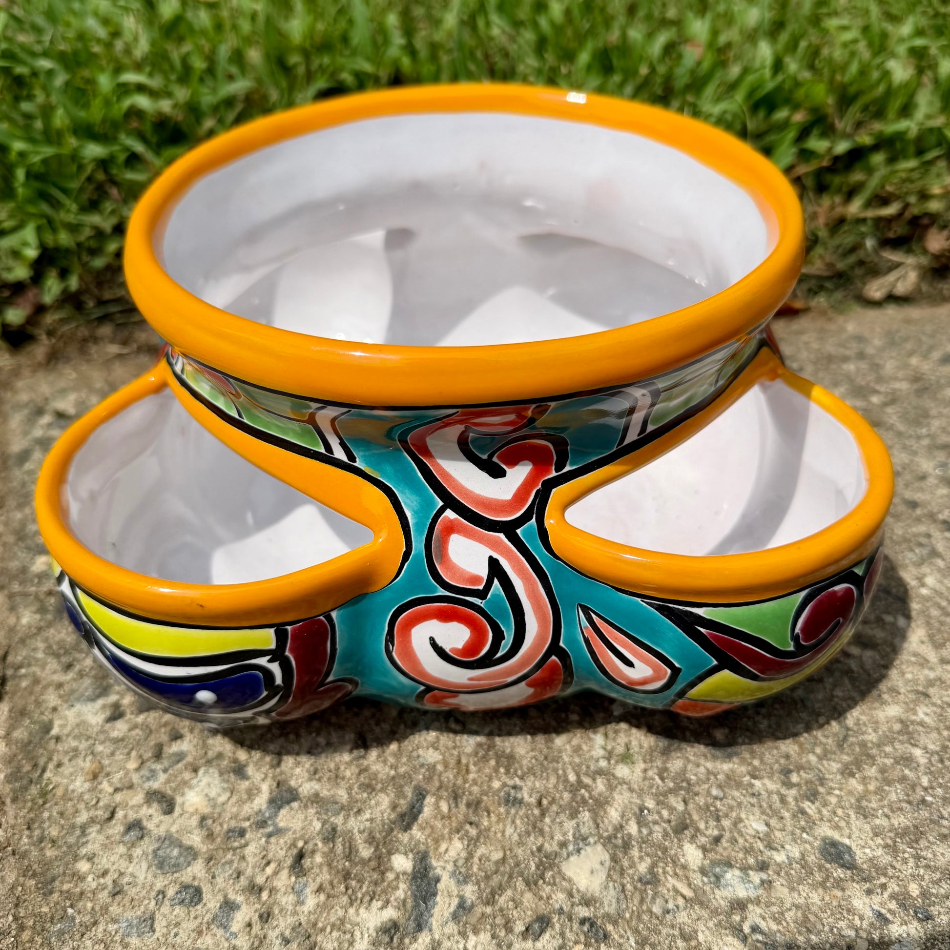 Hand painted Mexican Talavera Strawberry pot with a large top opening a four pockets on each side.  Trim color is bright happy yellow, body has multi-color designs on each of the four sides. Photo of the side.