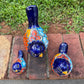 Three hand-painted ceramic bird figurines in different sizes, decorated with a vibrant Mexican Talavera style pattern of blue, red, yellow, and white, showing top view.

