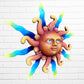 A whimsical sun wall sculpture with big blue eyes, a smiling face, and vibrant, left angle.