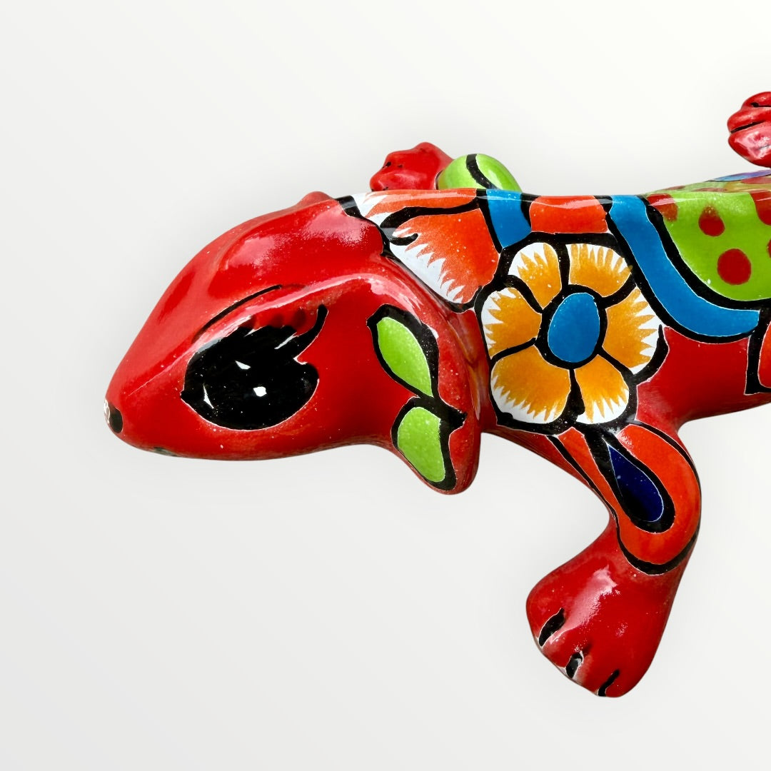 Mexican Talavera wall mounted iguana in bright red with multicolor designs face view.