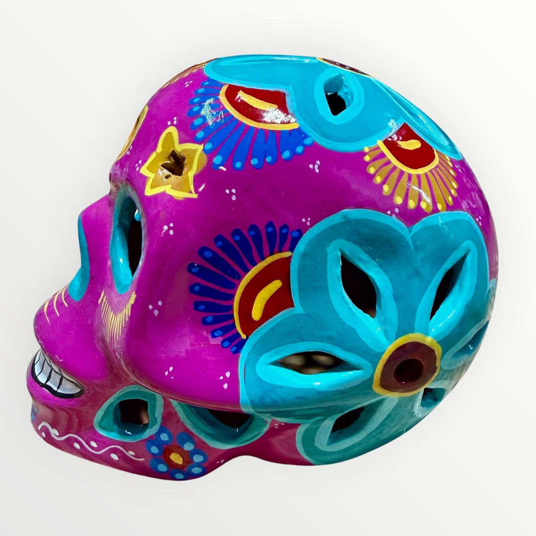 A hand-painted ceramic sugar skull in vibrant purple, turquoise blue, and yellow, decorated with floral and geometric patterns on a plain white background right side view.
