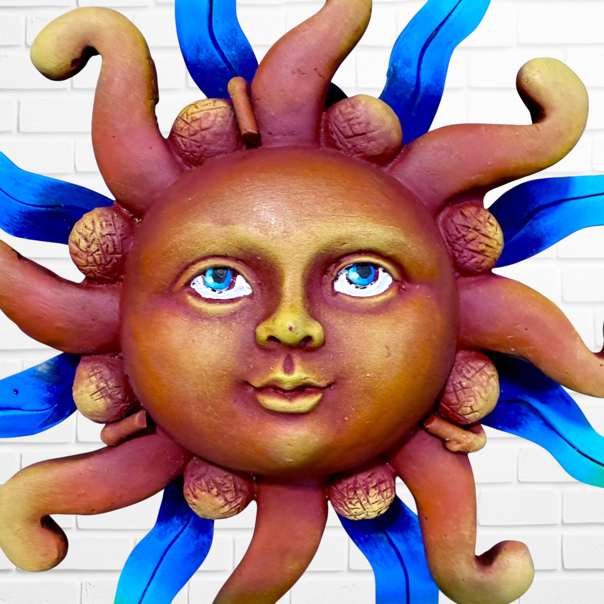 A whimsical sun wall sculpture with big blue eyes, a smiling face, and vibrant, face close up.