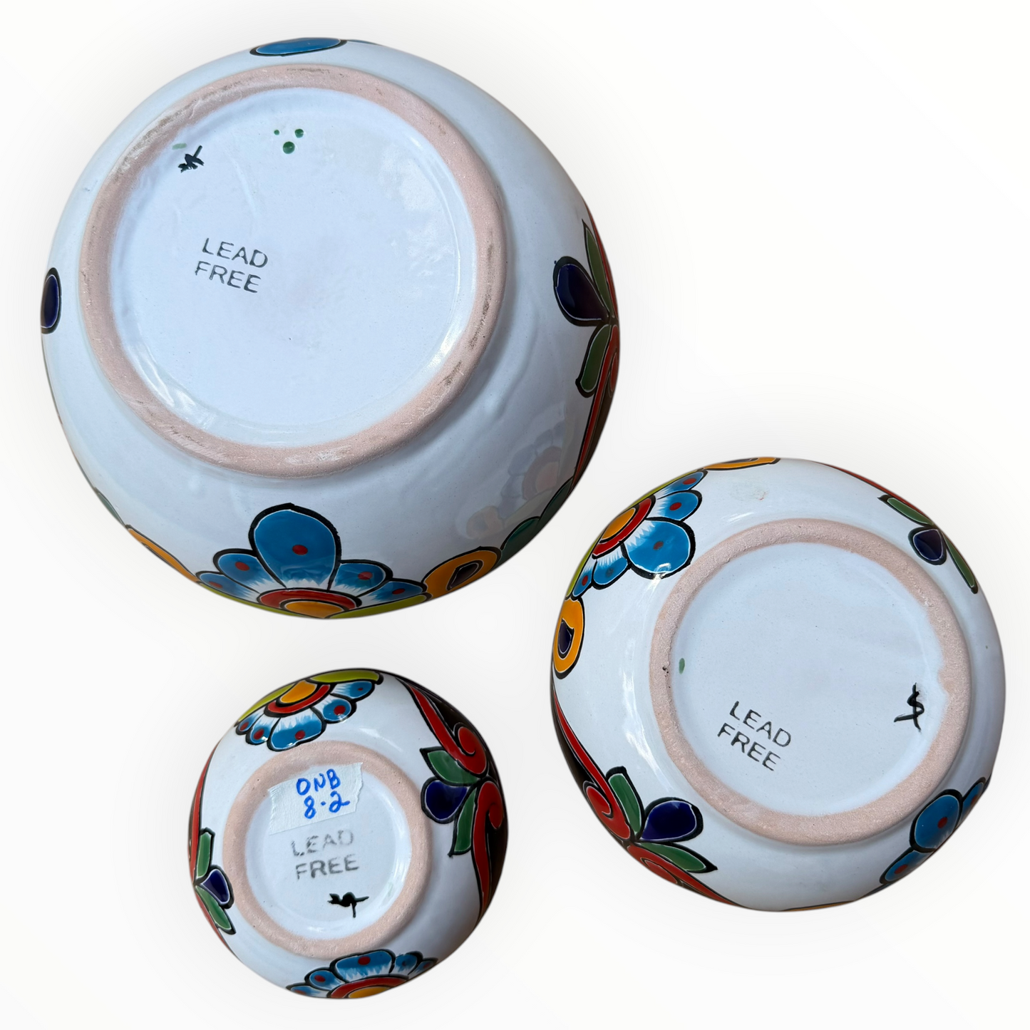 A set of three nested Talavera ceramic bowls with a vibrant hand-painted floral and geometric pattern in multiple colors, featuring a deep blue rim, shown on a plain white background, bottom view.