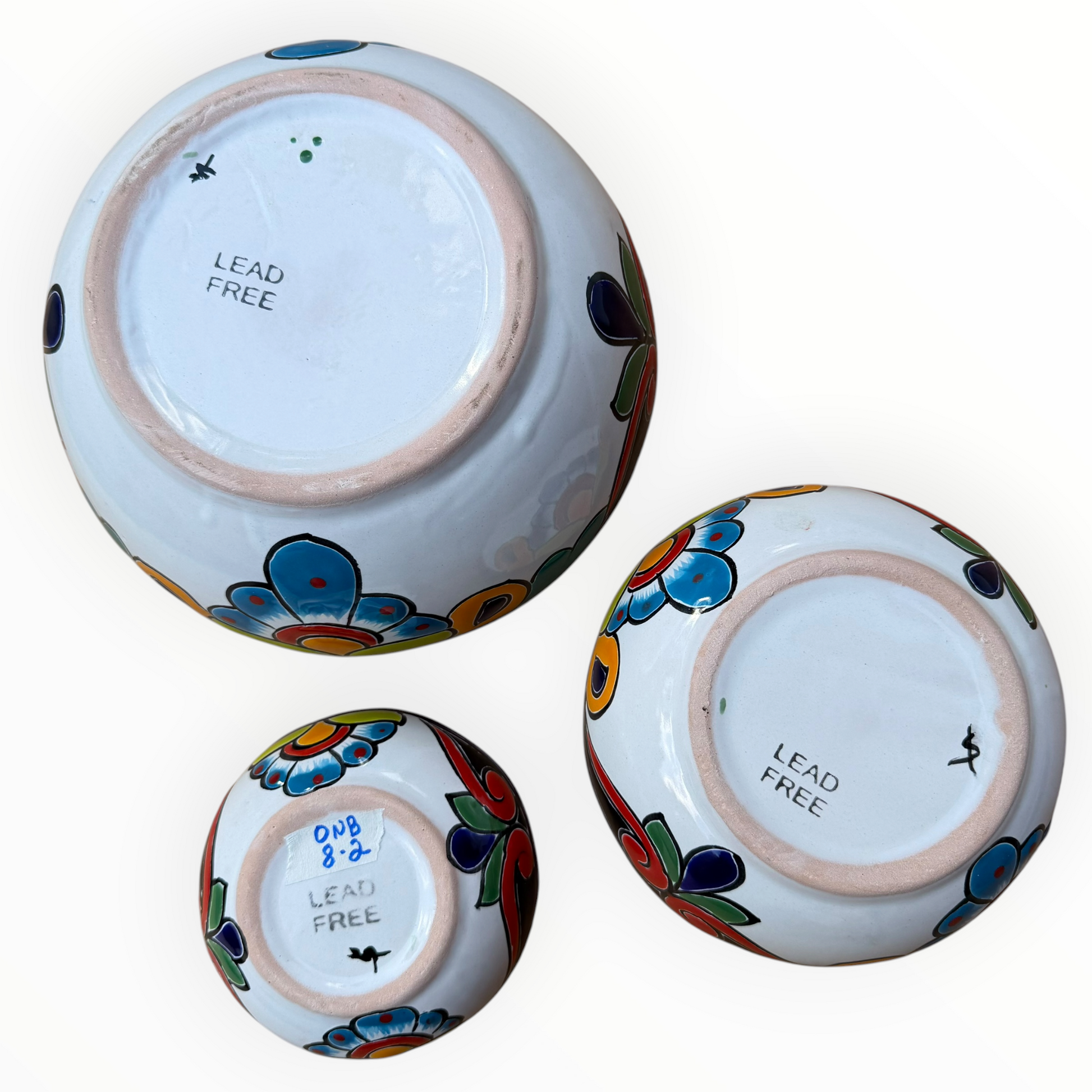 A set of three nested Talavera ceramic bowls with a vibrant hand-painted floral and geometric pattern in multiple colors, featuring a deep blue rim, shown on a plain white background, bottom view.