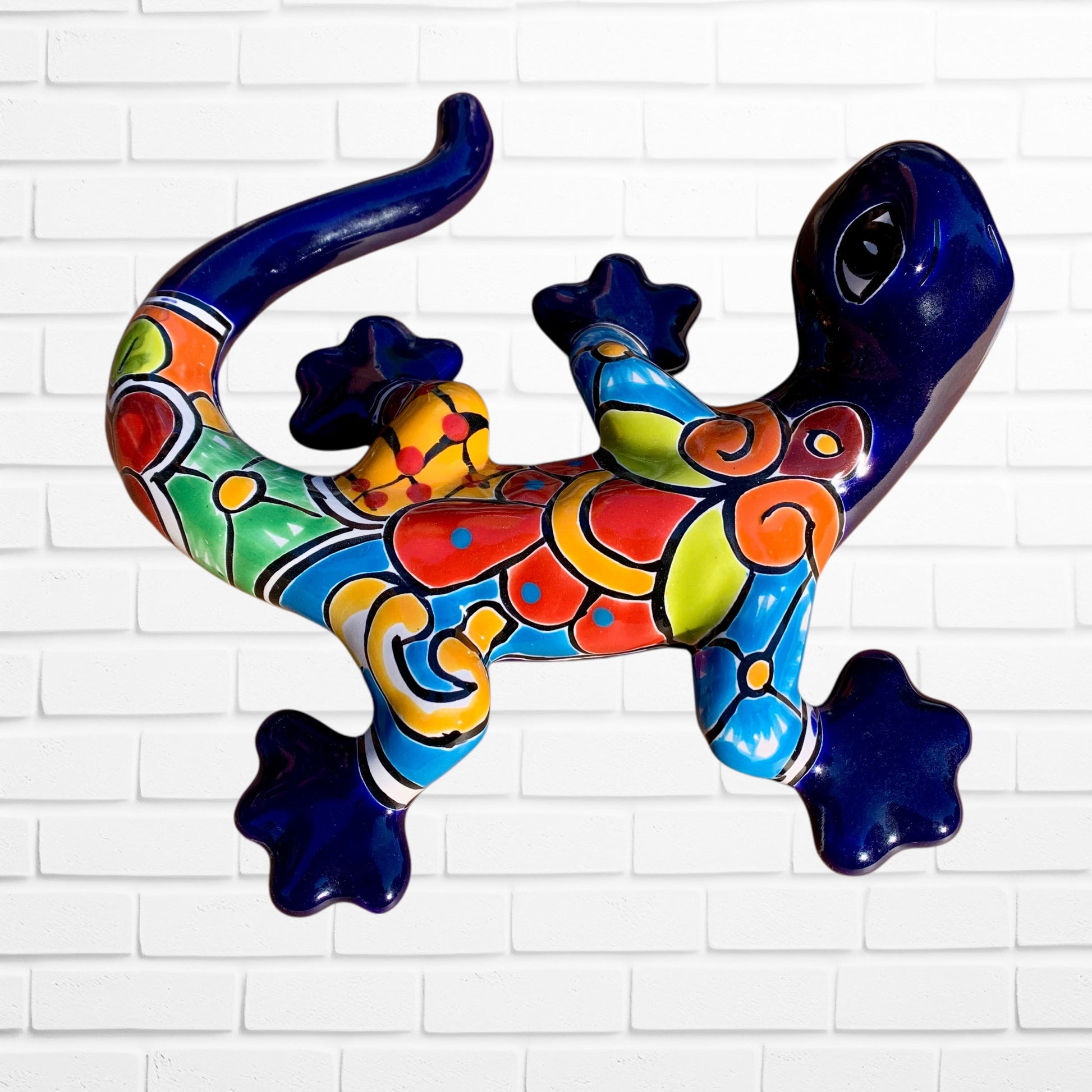 Colorful ceramic lizard wall art against a white brick wall background left side