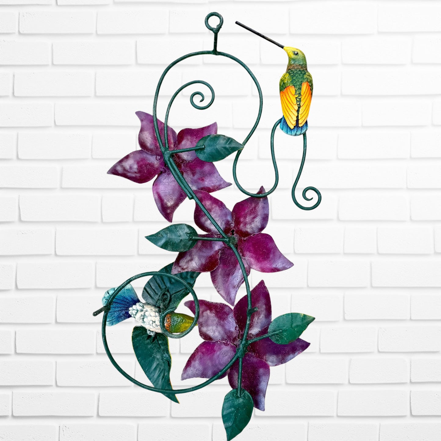 Decorative wall art with purple flowers and colorful hummingbirds on a white brick background back with hanging hook