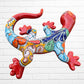 A colorful Talavera ceramic wall salamander lizard art piece with a glossy finish, featuring a red head and tail with a patterned body, displayed against a white brick wall background, right side body view.