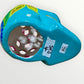 A decorative sugar skull painted in bright turquoise blue with colorful floral and geometric patterns in pink, yellow, green, purple, and white, shown against a plain light background bottom view.