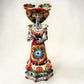 A colorful hand-painted talavera Day of the Dead (Día de los Muertos) skeleton figurine wearing a wide-brimmed sombrero and a floral dress, set against a plain off-white background.
