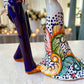 Mexican Talavera Catrina Bride and Groom dancing at their wedding.  He is wearing a tuxcedo with a top hat and she is wearing a flowing wedding dress with a veil and floral pattern toward the bottom.  Wedding dress floral detail close up.  