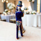 Mexican Talavera Catrina Bride and Groom dancing at their wedding.  He is wearing a tuxcedo with a top hat and she is wearing a flowing wedding dress with a veil and floral pattern toward the bottom.  Side view of couple featuring the groom and his tuxcedo tail.