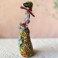 Mexican catrina talavera doll with calla lilies on the front of her dress. wearing a colorful dress with a big feathered hat.   Right side view showing the butterflies on her dress.