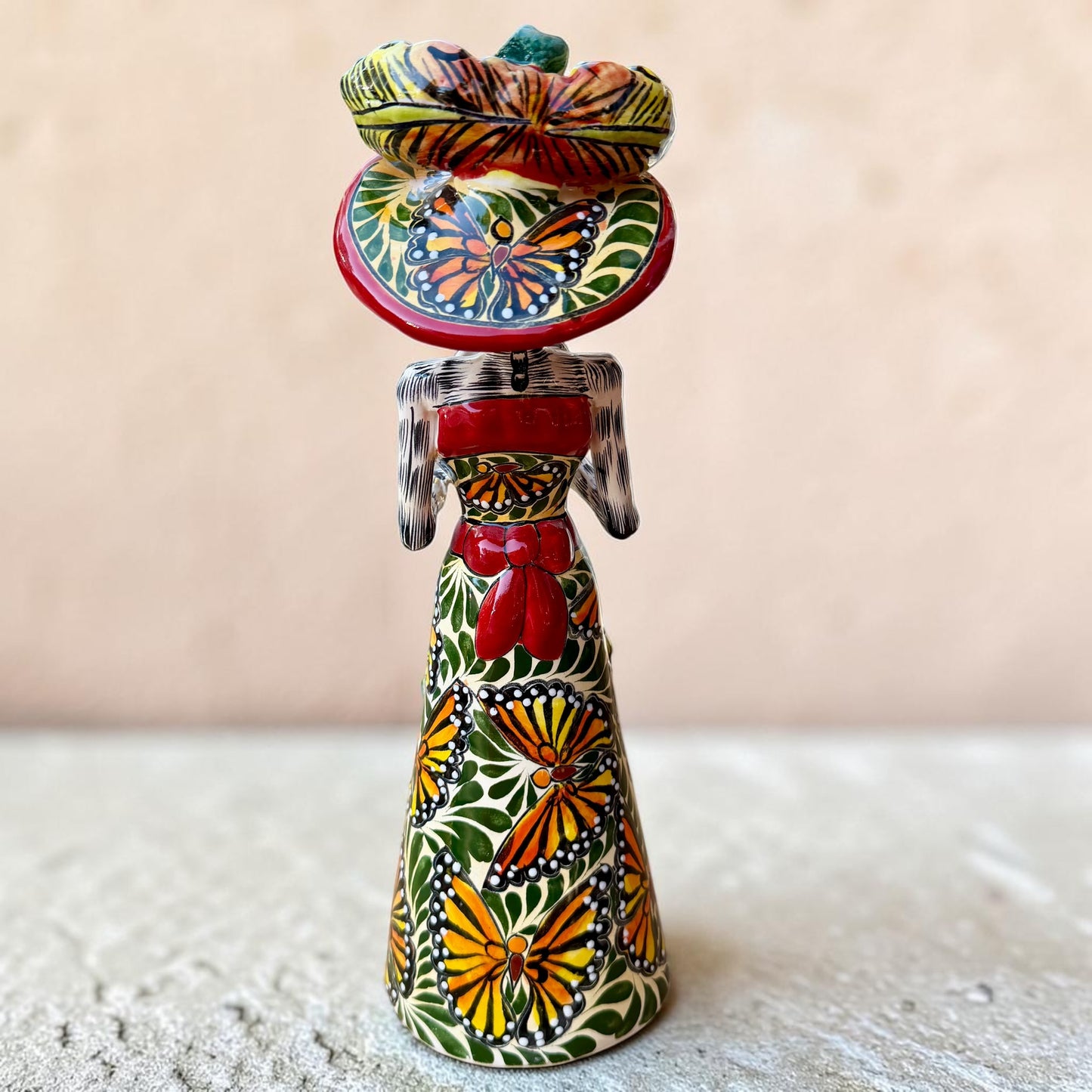 Mexican catrina talavera doll with calla lilies on the front of her dress. wearing a colorful dress with a big feathered hat.   Back View featuring the butterflies.