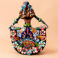 A colorful hand-painted Day of the Dead (Día de los Muertos) ceramic figurine of a  ballerina, decorated with vibrant floral patterns and a white skull head with braided hair, set against a solid peach background. Back side view of Ballerina doll.