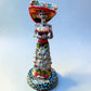 Mexican Catrina Doll made out of Talavera with Calla Lillies on the front of her dress.  Colorful pieces and a big feathered hat and a big toothy smile.